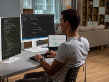 Programador trabalhando com três telas no computador