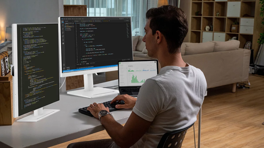 Programador trabalhando com três telas no computador